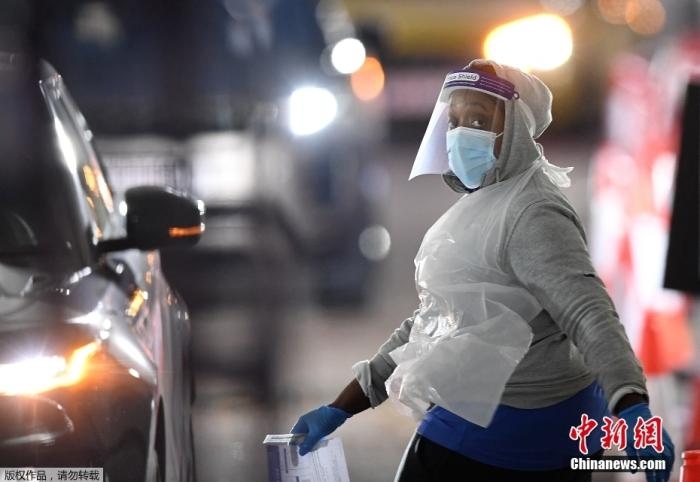 當(dāng)?shù)貢r間12月18日，英國政府公布的數(shù)據(jù)顯示，當(dāng)天英國新增奧密克戎毒株感染病例10059例。鑒于奧密克戎毒株感染病例激增，住院人數(shù)不斷上升，倫敦市長宣布倫敦進入“重大事故”狀態(tài)。圖為倫敦的一個免下車檢測中心，一名醫(yī)務(wù)工作者正準(zhǔn)備對司機進行核酸檢測。