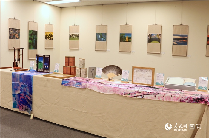 現(xiàn)場展出的馮學(xué)敏攝影作品與湖州市特色工藝品。（人民網(wǎng) 許可攝）