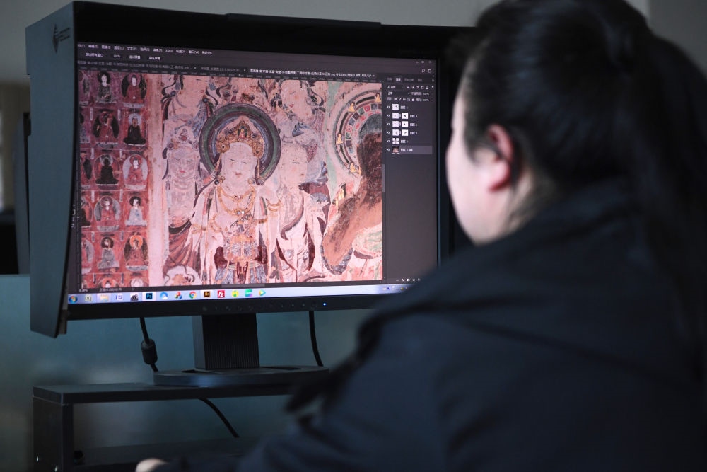 敦煌研究院文物數(shù)字化保護(hù)團(tuán)隊圖像處理人員年海麗在拼接壁畫圖像（2023年4月25日攝）。數(shù)字化探索為莫高窟的保護(hù)與傳承開辟了全新路徑，數(shù)字技術(shù)讓敦煌文物走出洞窟，跨出國門，走向“永久保存、永續(xù)利用”。新華社記者 陳斌 攝