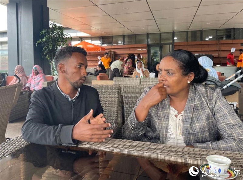 約漢斯（圖左）與德貝拉在友誼廣場咖啡廳交談。人民網(wǎng)記者 趙艷紅攝