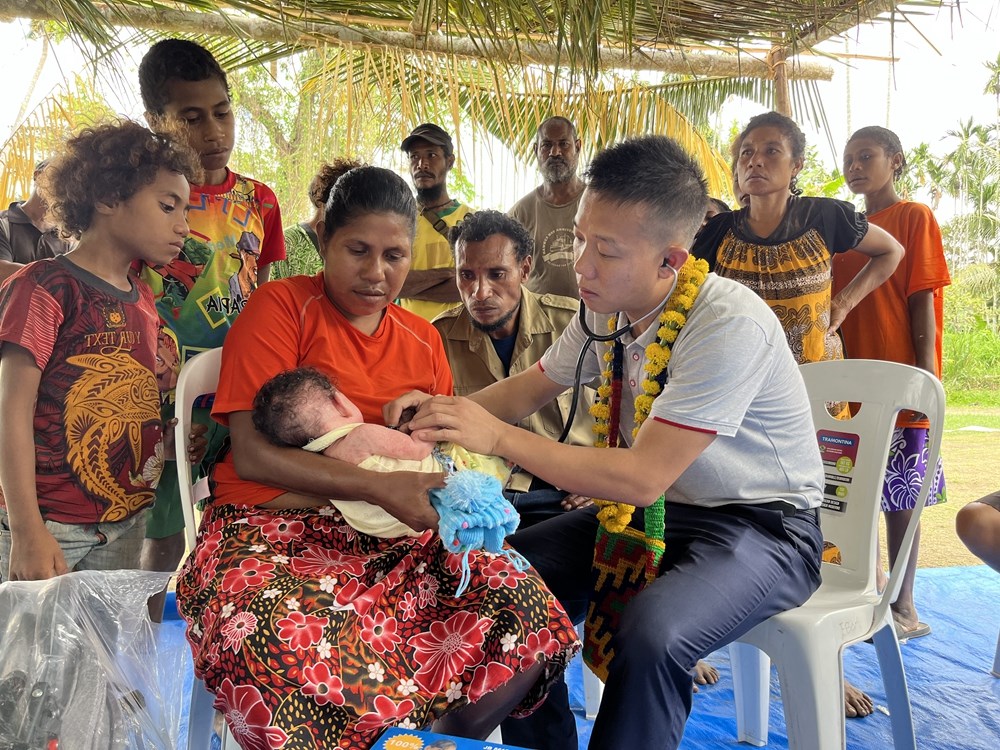 2023年8月5日，在巴布亞新幾內(nèi)亞中央省的一個(gè)村莊里，第12批援巴新中國(guó)醫(yī)療隊(duì)副隊(duì)長(zhǎng)、新生兒科副主任醫(yī)師劉振球?yàn)楫?dāng)?shù)貗雰郝犜\檢查。新華社發(fā)（第12批援巴新中國(guó)醫(yī)療隊(duì)供圖）