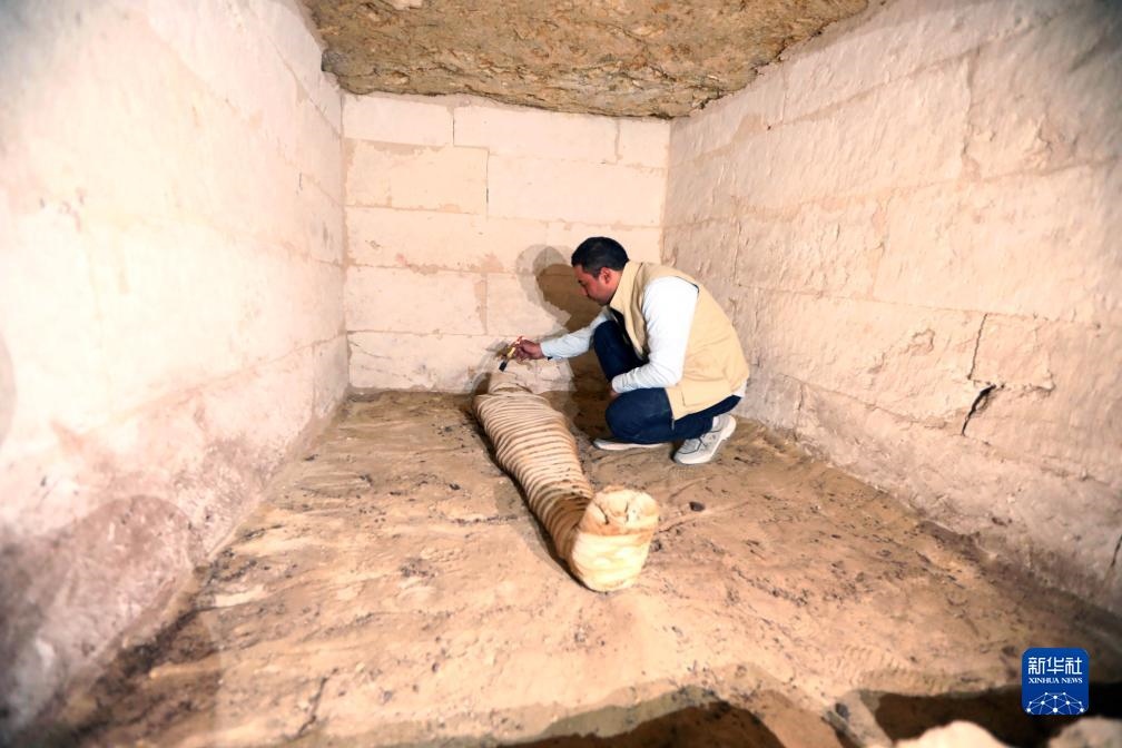 10月15日，在埃及明亞省考古現(xiàn)場(chǎng)，考古人員清理一座石鑿墓中的木乃伊。新華社發(fā)（艾哈邁德·戈馬攝）