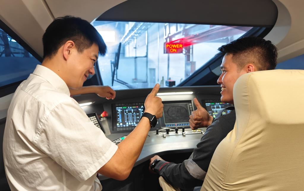 8月25日，在印度尼西亞萬隆的雅萬高鐵德卡魯爾動車所內(nèi)，中國師傅穆振（左）在向印尼火車司機(jī)塞蒂亞萬講解動車組出庫前的上電作業(yè)。