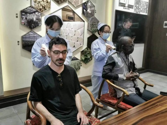2023“一帶一路”媒體合作論壇聯(lián)合采訪團團員在九牛草展示館體驗艾灸。（本報記者 黃超攝）