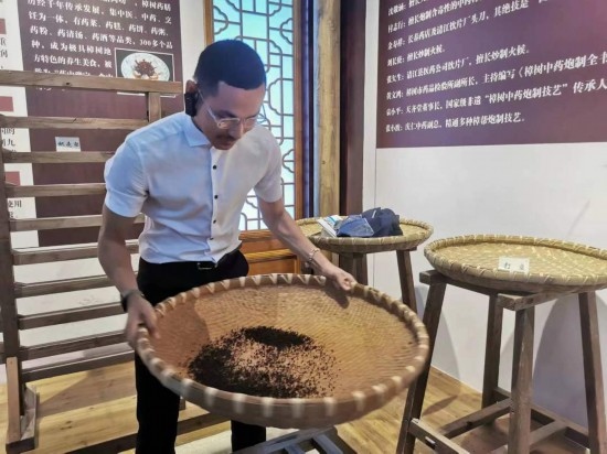 2023“一帶一路”媒體合作論壇聯(lián)合采訪團團員在非遺文化展示館體驗中藥炮制技藝。（本報記者 黃超攝）