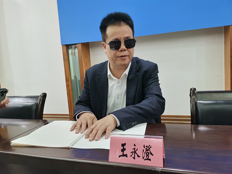 全國人大代表王永澄正在閱讀盲文版代表建議答復(fù)。本報記者 張 璁?dāng)z