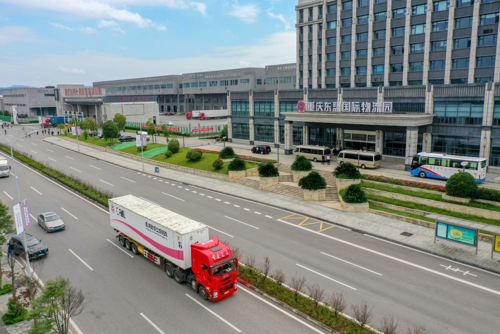 2023年10月11日，滿載筆記本電腦配件、發(fā)電機(jī)組件等產(chǎn)品的西部陸海新通道跨境公路班車從重慶南彭公路保稅物流中心駛出，將途經(jīng)廣西憑祥，直達(dá)越南（無人機(jī)照片）。新華社記者 黃偉 攝