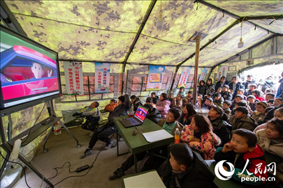 12月22日，在積石山縣大河家鎮(zhèn)大河村安置點(diǎn)，陸軍76集團(tuán)軍某旅搭建的“臨時(shí)學(xué)?！眱?nèi)，小朋友正在看動(dòng)畫(huà)片。人民網(wǎng)記者 翁奇羽攝