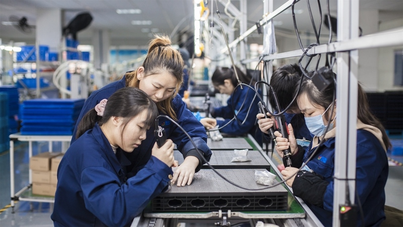 在新亞勝光電的產(chǎn)品線上，工人正進行產(chǎn)品組建和安裝布線。受訪者供圖