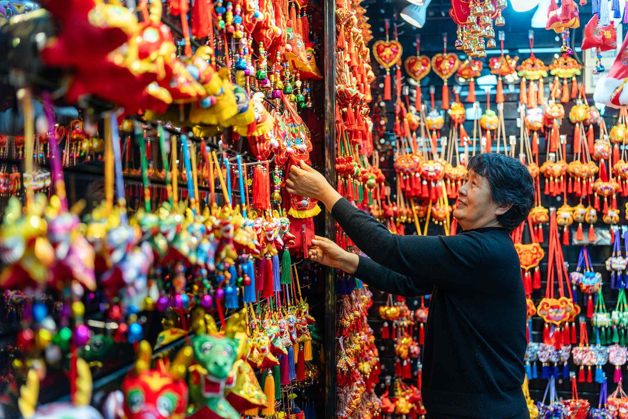 2023年12月11日，金華義烏國際商貿城，龍年喜慶用品掛滿攤位，顧客正在挑選中。