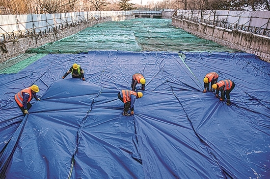 1月3日，房山區(qū)東風街道，工人正在修復(fù)的河道內(nèi)給混凝土鋪設(shè)保溫布。