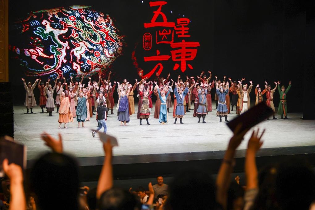 2023年7月31日，新疆和田地區(qū)新玉歌舞團(tuán)在烏魯木齊京劇院演出舞劇《五星出東方》后和觀眾互相揮手致意。這場(chǎng)演出是第六屆中國(guó)新疆國(guó)際民族舞蹈節(jié)的參演劇目之一，曾榮獲國(guó)家“文華獎(jiǎng)”等。新華社記者 郝昭 攝