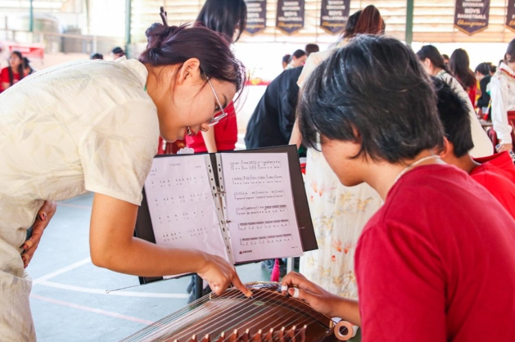 志愿者教師指導(dǎo)學(xué)生彈奏古箏?；顒又鬓k方供圖