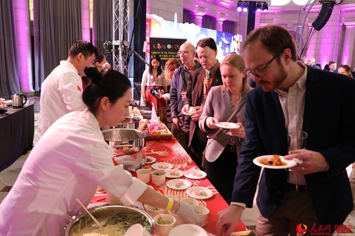 當(dāng)?shù)貢r間3月7日晚，華盛頓聯(lián)合車站廣場舉行駐美使團(tuán)“使館主廚挑戰(zhàn)賽”。圖為當(dāng)?shù)孛癖娫谥袊古_前體驗中國美食。人民網(wǎng)記者 李志偉攝