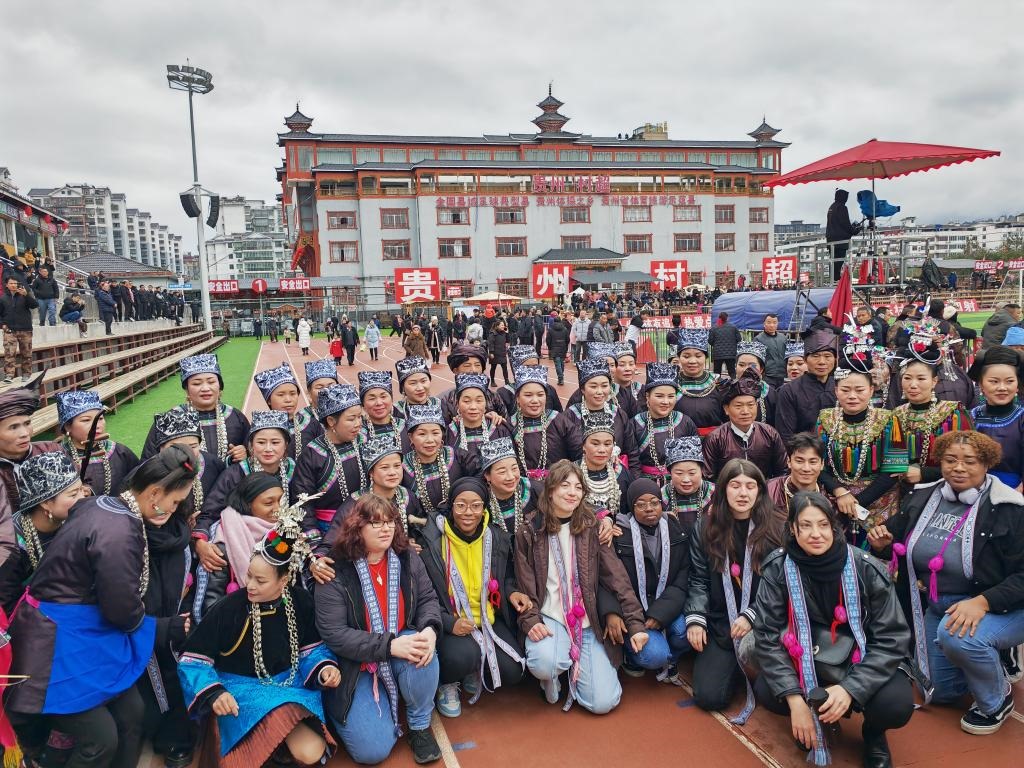 法國青年在“村超”賽場邊與參加表演的村民合影。新華社記者 羅羽 攝