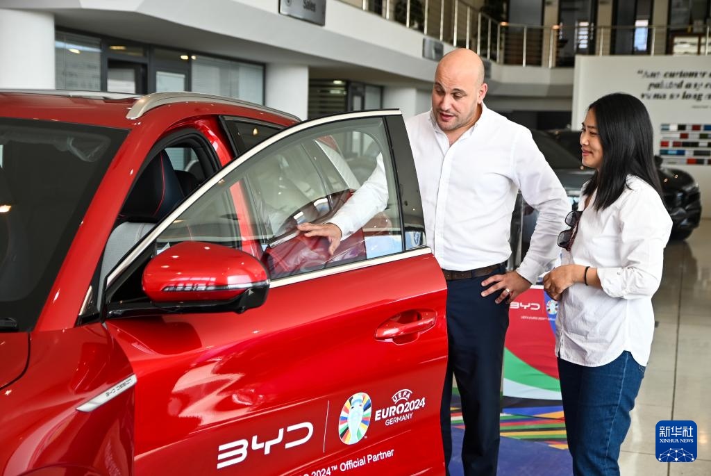 2024年5月29日，在馬耳他比爾基卡拉，馬耳他哈桑-扎米特汽車公司首席執(zhí)行官德古阿拉（左）介紹一輛比亞迪純電動汽車。新華社發(fā)（喬納森·博格 攝）