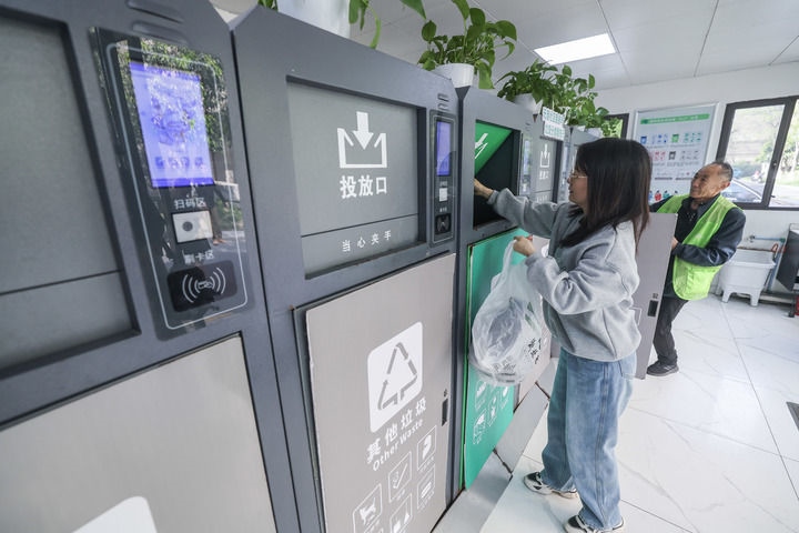 2024年4月10日，在浙江省湖州市吳興區(qū)飛英街道新華府小區(qū)內(nèi)，居民在垃圾分類智能系統(tǒng)的指導(dǎo)下進行垃圾分類投放，居民的投放情況將實時匯總到智慧服務(wù)平臺，會有相應(yīng)的積分獎勵。新華社記者 徐昱 攝