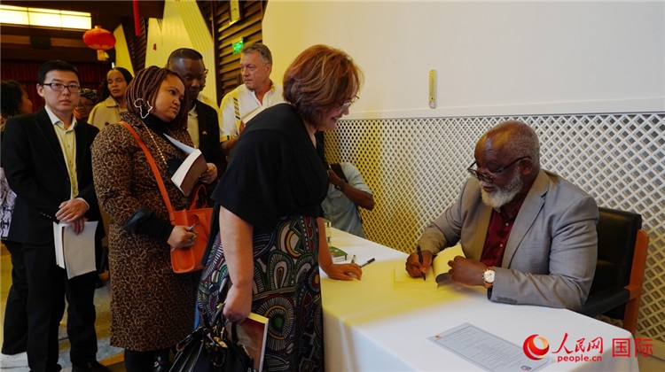 譚哲理在活動現(xiàn)場簽名贈書。人民網(wǎng) 劉暢攝