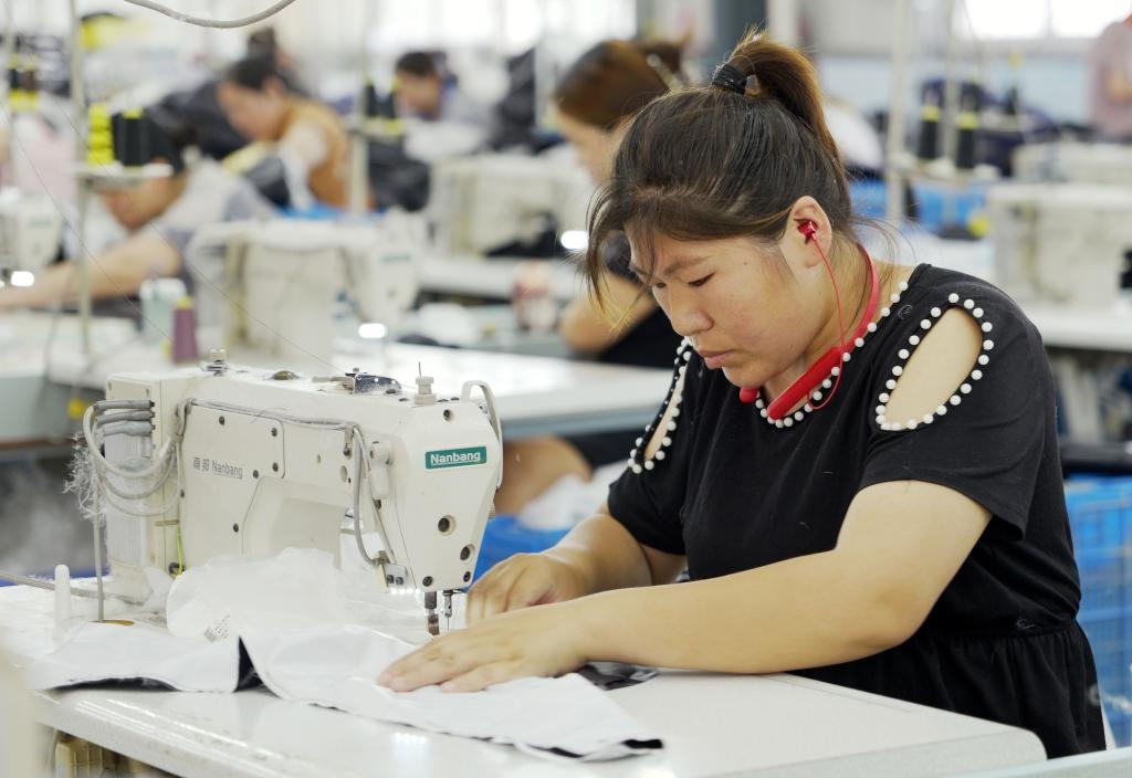 5月20日，村民在李寨村服裝加工廠內(nèi)忙碌。河南省周口市沈丘縣馮營鎮(zhèn)李寨村地處豫東平原。近年來，乘著脫貧攻堅(jiān)與鄉(xiāng)村振興政策的東風(fēng)，李寨村積極探索產(chǎn)業(yè)發(fā)展模式，通過“龍頭企業(yè)+村集體經(jīng)濟(jì)+農(nóng)戶”的方式，逐漸發(fā)展形成肉牛養(yǎng)殖、設(shè)施農(nóng)業(yè)、服裝加工、康養(yǎng)民宿等產(chǎn)業(yè)，以產(chǎn)業(yè)振興助力鄉(xiāng)村振興。新華社記者 李嘉南 攝