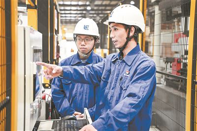 在廣西柳工機械股份有限公司生產(chǎn)車間內(nèi)，一名高級技師（右）給徒弟講解數(shù)控設備操作細節(jié)。新華社記者 曹祎銘攝