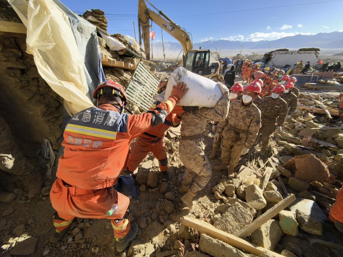 1月11日，定日縣長(zhǎng)所鄉(xiāng)古榮村，應(yīng)急消防等救援人員排隊(duì)接力搶運(yùn)掩埋在倒塌房屋下的群眾財(cái)物。人民日?qǐng)?bào)記者楊翹楚攝
