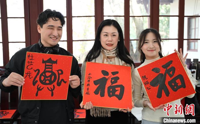 1月20日，外籍留學生和西泠印社社員李硯(中)展示各自創(chuàng)作的福貼。當日，來自巴西、馬來西亞、加納、哈薩克斯坦的外籍留學生在浙江杭州西泠印社體驗福貼、春聯(lián)和篆刻，感受古老的中國傳統(tǒng)文化。中新社記者 王剛 攝