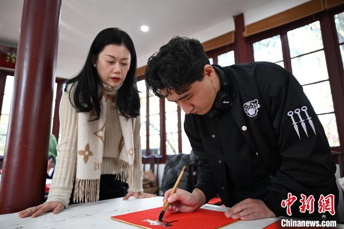 1月20日，外籍留學生在西泠印社社員李硯指導(dǎo)下寫福。當日，來自巴西、馬來西亞、加納、哈薩克斯坦的外籍留學生在浙江杭州西泠印社體驗福貼、春聯(lián)和篆刻，感受古老的中國傳統(tǒng)文化。中新社記者 王剛 攝