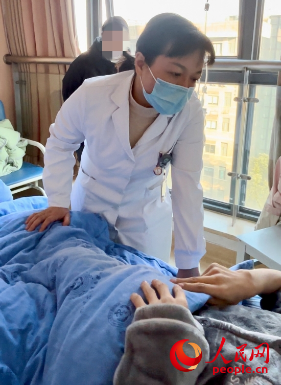 鄧茜查房時(shí)詢問(wèn)患者情況。人民網(wǎng)記者 金慧慧攝