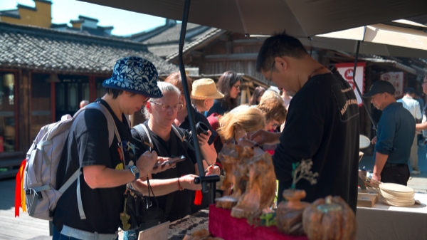 “五一”期間，游客正在烏鎮(zhèn)“水鄉(xiāng)碼頭”挑選購買文創(chuàng)產(chǎn)品。受訪者供圖