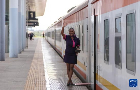 5月31日，在蒙內(nèi)鐵路內(nèi)羅畢站，一名乘務(wù)員在即將開往蒙巴薩的E2次列車旁等候乘客。新華社記者 李亞輝 攝
